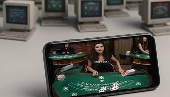 A new online casino on a smartphone displays a live casino game, with old casinos on old computers in the background.