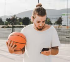 young man holiding basketball and mobile phone