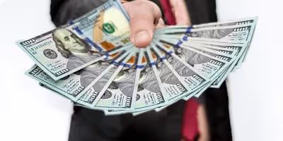 Hand holding a fan of US hundred-dollar bills