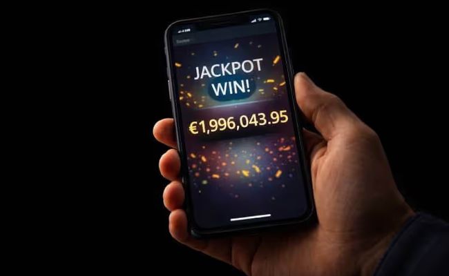 Hand holding a mobile phone showing a nearly €2 million progressive jackpot win