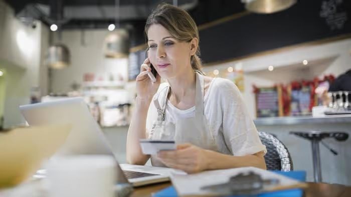 Woman on phone with credit card and laptop